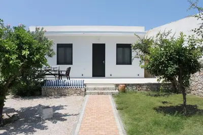 a white house with black doors and a brick pathway at ELÉNAS slow living villa in Faliraki