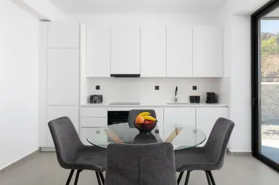 a person sitting at a glass table in a kitchen at Zen Club Luxury Villas in Kolimbia