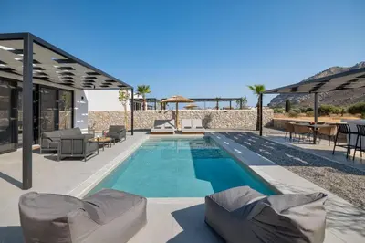 a swimming pool with chairs and tables and a building at Zen Club Luxury Villas in Kolimbia
