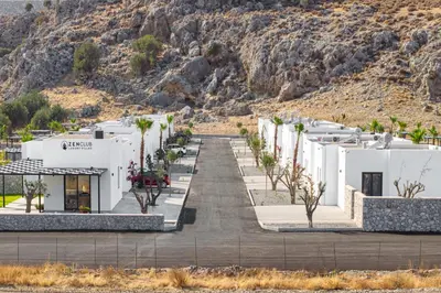 a row of white buildings in front of a mountain at Zen Club Luxury Villas in Kolimbia