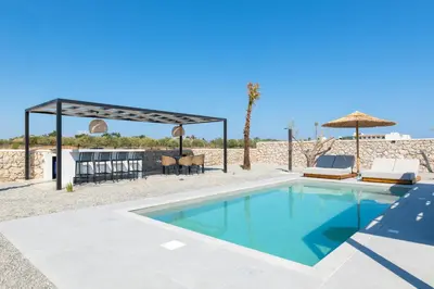 a swimming pool with chairs and a table and umbrella at Zen Club Luxury Villas in Kolimbia