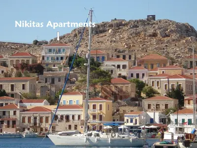 a sail boat docked in a harbor with houses at Nikitas Studio in Halki