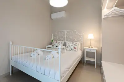 a small white bedroom with a crib and a side table at Villa Basilio in Gennadi