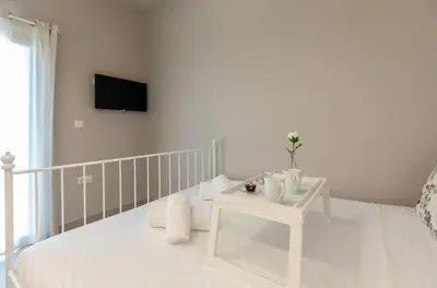 a white bedroom with a bed and a tv on the wall at Villa Basilio in Gennadi