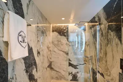 a bathroom with a shower with a marble wall at Monarco Executive Rooms in Rhodes Town