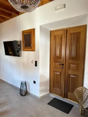 a room with a wooden door and a tv on a wall at Tapanis luxury house in Líndos