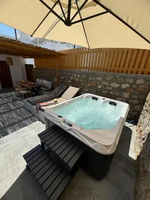 a hot tub on a patio with an umbrella at Tapanis luxury house in Líndos