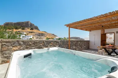 a hot tub on a stone wall with a table at Tapanis luxury house in Líndos