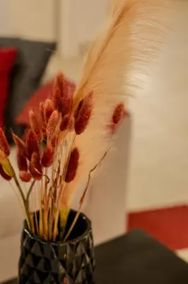 a black vase with some dried flowers in it at Ismini Basement Retreat in vlicha