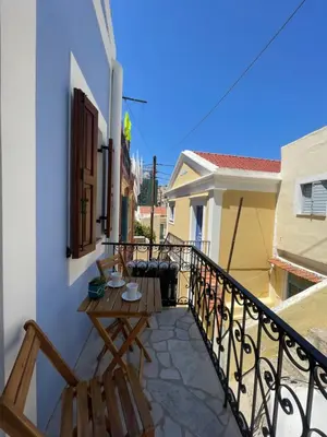 a balcony with a table and chairs on a building at Serenity Luxury Apartment in Symi