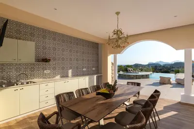 a kitchen and dining room with a wooden table and chairs at Ralu Villa - Faliraki & Traganou Beach in Kalithies