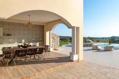 an open kitchen and dining room with a table and chairs at Ralu Villa - Faliraki & Traganou Beach in Kalithies