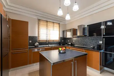 a kitchen with wooden cabinets and a black counter top at Ralu Villa - Faliraki & Traganou Beach in Kalithies