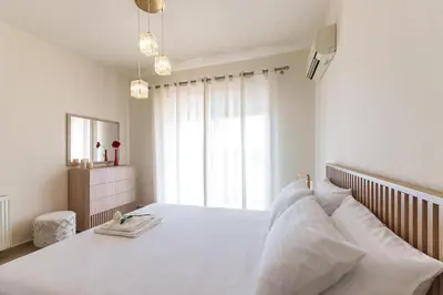 a bedroom with a bed with white sheets and a window at Mira Villa - Faliraki & Traganou Beach in Kalithies