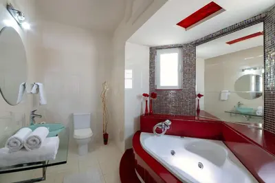 a white bathroom with a red tub and a toilet at Mira Villa - Faliraki & Traganou Beach in Kalithies