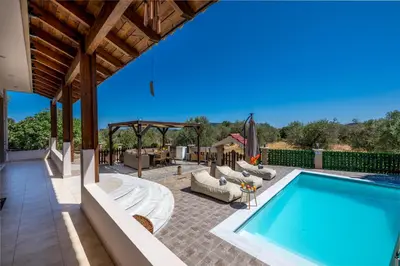 a patio with a swimming pool and chairs and a table at Thalpori Villa in Pastida