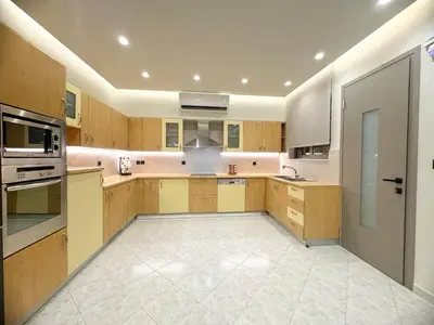 a large kitchen with wooden cabinets and stainless steel appliances at Grand Aqua Luxury Villa by Mintzi in Yennadhion