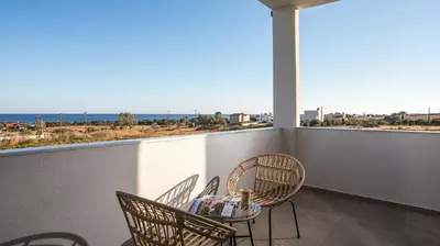 a balcony with chairs and a table and a view of the ocean at Grand Aqua Luxury Villa by Mintzi in Yennadhion