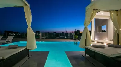 a swimming pool at night with umbrellas at Grand Aqua Luxury Villa by Mintzi in Yennadhion
