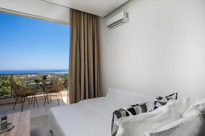 a hotel room with a bed and a large window at Zafora Apartment in Koskinou