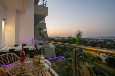 a balcony with a table with two bottles of wine at Zafora Apartment in Koskinou