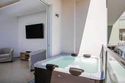 a tub in a room with a tv and a living room at Zafora Apartment in Koskinou