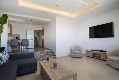 a living room with a blue couch and a tv at Zafora Apartment in Koskinou