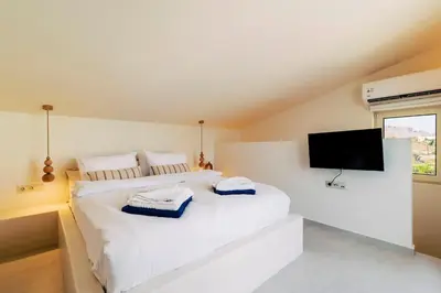 a bedroom with two white beds and a flat screen tv at 3 Villa Complex in Kiotari
