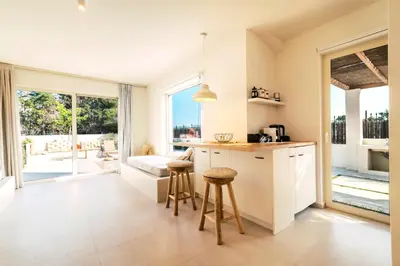 a kitchen with white cabinets and a counter with stools at 3 Villa Complex in Kiotari