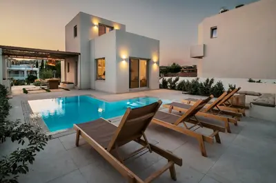 a backyard with a swimming pool and chairs and a house at 3 Villa Complex in Kiotari