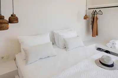 a white bed with white pillows and a hat on it at 3 Villa Complex in Kiotari