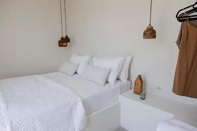 a white bedroom with a bed with white sheets and pillows at 3 Villa Complex in Kiotari