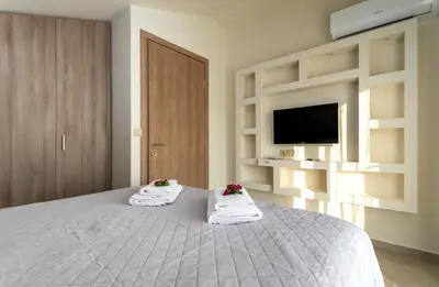 a bedroom with a bed with towels and a tv at Villa Hodaj in Afantou