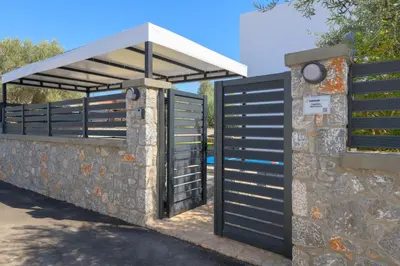 a gate with a roof on a stone wall at Villa Lambis Harmonia in Líndos