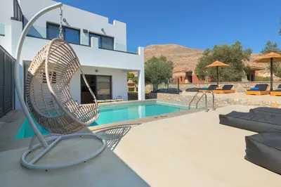 a swinging chair next to a swimming pool at Villa Lambis Harmonia in Líndos
