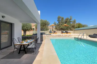 a patio with a table and chairs next to a swimming pool at Villa Lambis Harmonia in Líndos