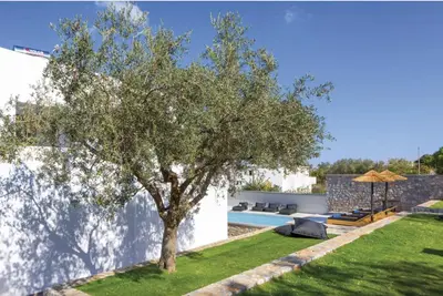 a tree in a yard next to a pool at Villa Lambis Athena in Líndos