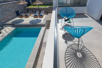 a view of a swimming pool with two chairs and a table at Villa Lambis Athena in Líndos