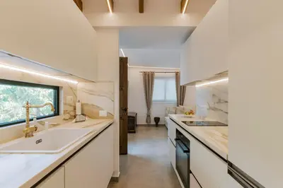a kitchen with white counters and a sink and a window at La Casetta della Nonna in Lardos