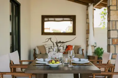 a wooden table with a bowl of fruit and wine glasses at La Casetta della Nonna in Lardos
