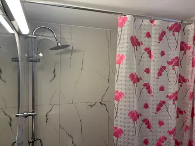 a shower curtain with pink flowers on it in a bathroom at Haus Rosi in Rhodes Town
