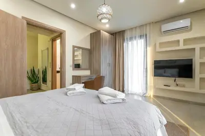 a bedroom with a large white bed and a flat screen tv at Villa Hodaj 2 in Afantou