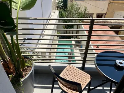 a balcony with two chairs and a table and some plants at Triekmo Pyr in Rhodes Town