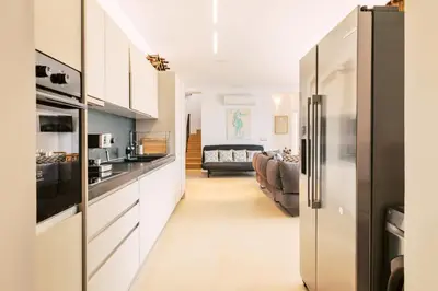 a kitchen with white cabinets and a living room at Mythica Luxury Villa in Yennadhion