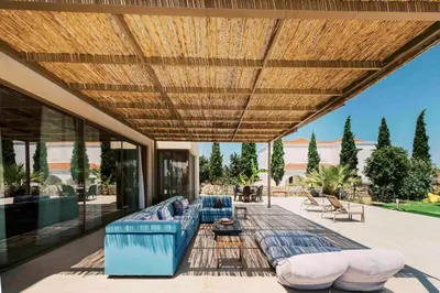 a patio with a blue couch under a wooden roof at Mythica Luxury Villa in Yennadhion