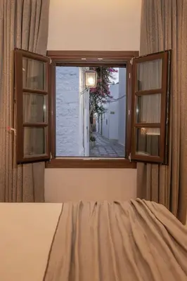 a bedroom with a window with a view of a street at Kantouni Lindos ELEGANT APARTMENT in Líndos
