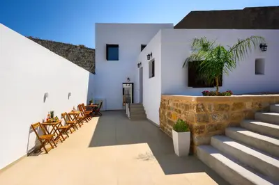 a courtyard of a house with stairs and chairs at Aroha Apartments in Rhodes Town