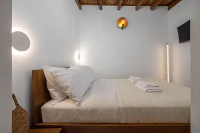 a bedroom with a bed with white sheets and pillows at Aroha Apartments in Rhodes Town