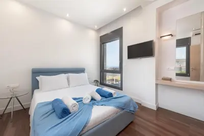 a bedroom with a bed with blue sheets and a tv at Kiotari Dream beachfront villa in Gennadi
