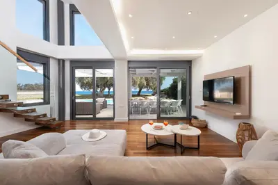 a living room with a couch and a tv at Kiotari Dream beachfront villa in Gennadi